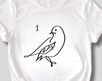 May include: White t-shirt featuring a minimalist black line drawing of a bird with the number "1" above it. The bird has the word "Mary" inside its wing. The shirt has a crew neck and short sleeves.