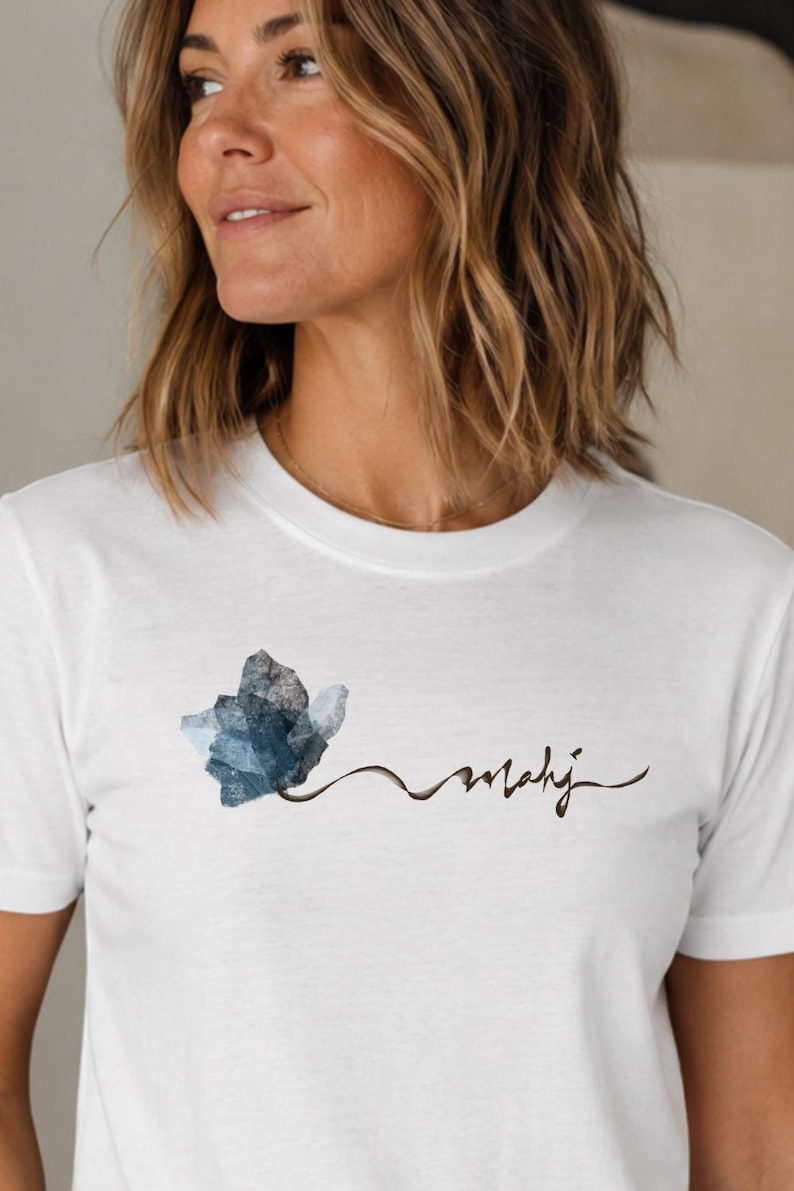 May include: White t-shirt featuring a blue watercolor floral design and the word "mahij" in a handwritten font. The shirt is made of a soft, comfortable material.