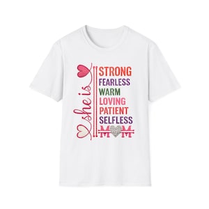 May include: White t-shirt with the words "She is" in pink script and a heart design. The shirt features the words "Strong, Fearless, Warm, Loving, Patient, Selfless, Mom" in various colors.
