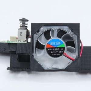 May include: A black electronic component featuring a clear fan with blue, red, and green accents. The fan is housed in a black frame, with a circuit board and spring mechanism attached. The text "DC 24V LED" is visible.