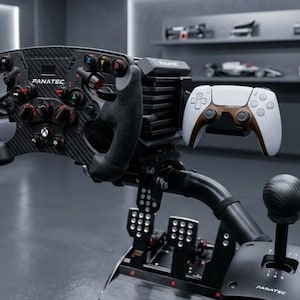 May include: A black carbon fiber Fanatec racing steering wheel with multiple buttons and knobs, a white and black game controller mounted to the side, a black gear shifter, and a set of three metal pedals on a black frame with a central support.