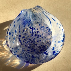 May include: A clear glass bowl with a blue and white swirl pattern. The bowl has a textured surface with small blue dots and a white swirl design.