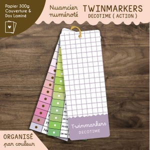 Könnte beinhalten: Ein Satz von Twinmarkers Decotime Farbmusterkarten. Die Karten sind fächerförmig angeordnet und zeigen verschiedene Farben und Schattierungen. Die Karten haben ein Rastermuster und enthalten den Text "Twinmarkers Decotime". Der Hintergrund ist eine Holzoberfläche.