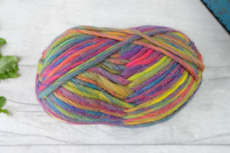 May include: A ball of colorful yarn with shades of pink, purple, blue, green, and yellow. The yarn is made of wool and is perfect for knitting or crocheting.