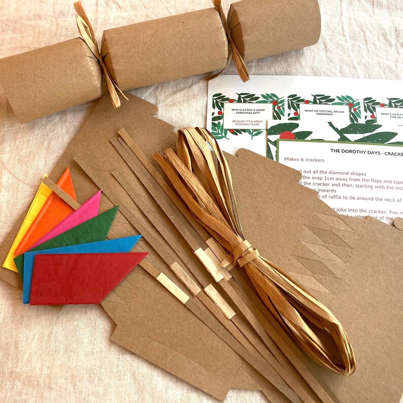 May include: A craft kit for making six Christmas crackers. The kit includes brown paper tubes, brown paper strips, brown paper diamond shapes, colorful paper flags, and brown raffia ribbon. The instructions on the card read "The Dorothy Days - Cracker Kit".