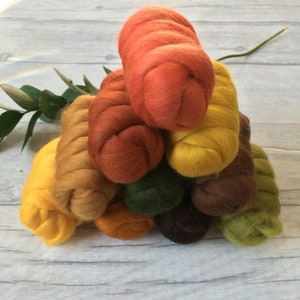 Peut inclure: Une collection de 10 laines card&eacute;es de diff&eacute;rentes couleurs, dispos&eacute;es en forme de pyramide. Les couleurs sont des nuances de jaune, d'orange, de brun et de vert.