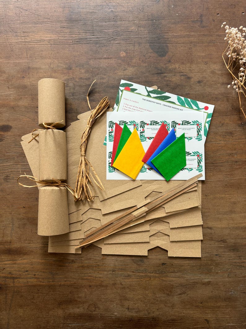 Christmas Cracker Kit. The photo shows a made up Christmas cracker which you can make with the kit plus everything the kit contains. Premium hats, jokes and instructions on a festive design background, snaps and raffia