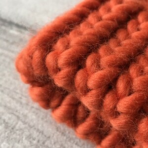 Puede incluir: Primer plano de una tela de punto de color naranja quemado. La tela es gruesa y tiene una textura de punto grueso.