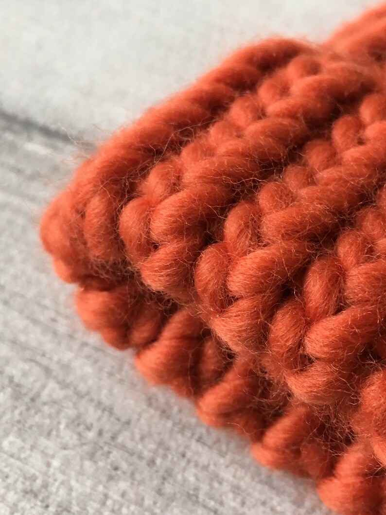 Puede incluir: Primer plano de una tela de punto de color naranja quemado. La tela es gruesa y tiene una textura de punto grueso.