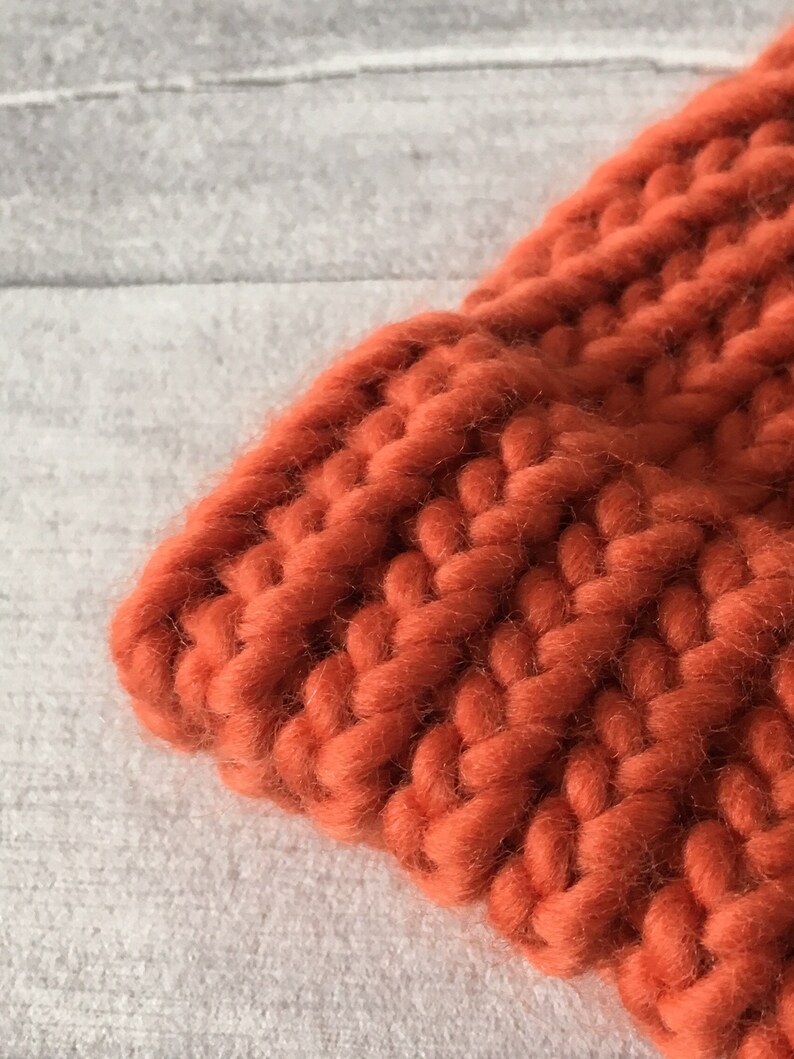 Puede incluir: Primer plano de una tela de punto grueso de color naranja quemado. La tela est&aacute; hecha de hilo grueso y tiene una textura suave y peluda.