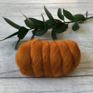 Peut inclure: Un gros plan d'un rouleau de laine orange. La laine est dispos&eacute;e en spirale et est pr&ecirc;te pour le feutrage.