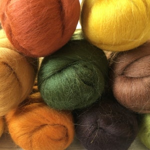 Peut inclure: Un ensemble de huit pelotes de laine de diff&eacute;rentes couleurs, dont l'orange, le jaune, le vert, le marron et le marron fonc&eacute;. Les pelotes de laine sont dispos&eacute;es en cercle, avec la pelote orange au centre.