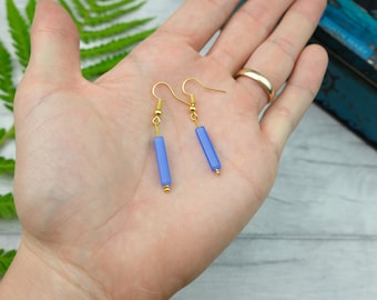 May include: A pair of gold earrings with light blue rectangular beads.