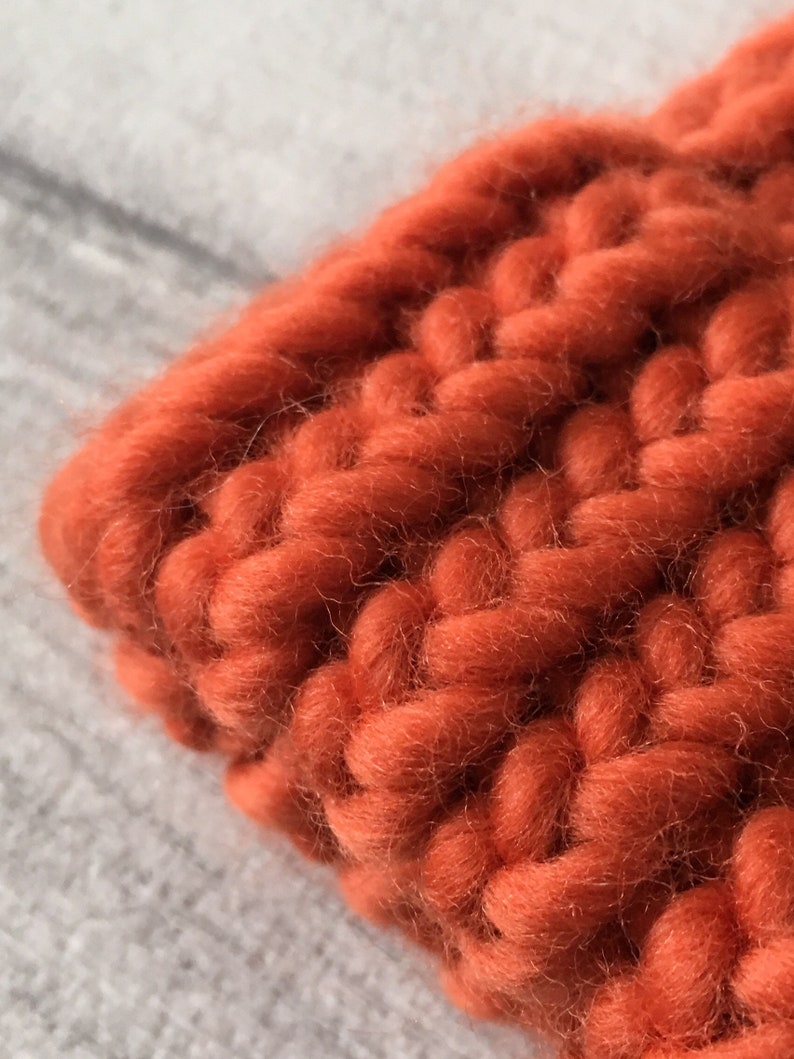 Puede incluir: Primer plano de una tela de punto grueso de color naranja quemado. La tela est&aacute; hecha de hilo grueso y tiene una textura suave y peluda.