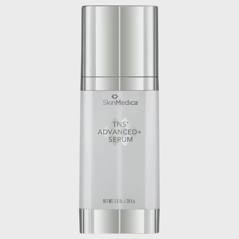 May include: A cylindrical SkinMedica TNS ADVANCED+ SERUM bottle with a metallic silver cap and base. The white label features the brand name, product name, and the text NET WT. 1.0 Oz. / 28.4 g printed in a clear, dark font on the front surface.
