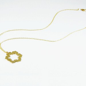 May include: A gold chain necklace with a delicate, openwork flower pendant.