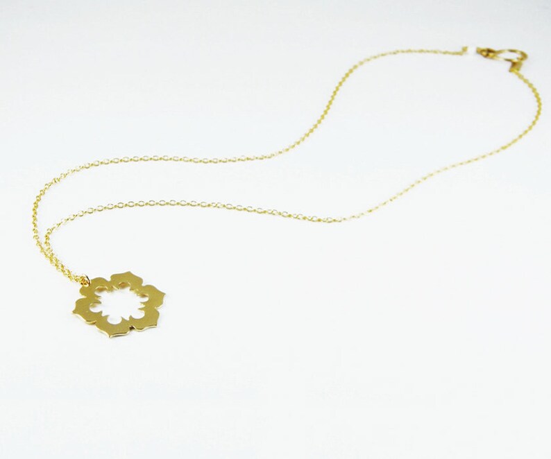 May include: A gold chain necklace with a delicate, openwork flower pendant.