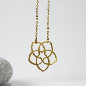 May include: Gold necklace with a geometric flower pendant. The pendant is made of a single piece of metal and has a delicate, intricate design.