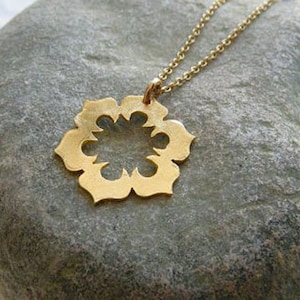 May include: A gold necklace with a delicate, openwork pendant shaped like a flower. The pendant has a circular center and eight points.