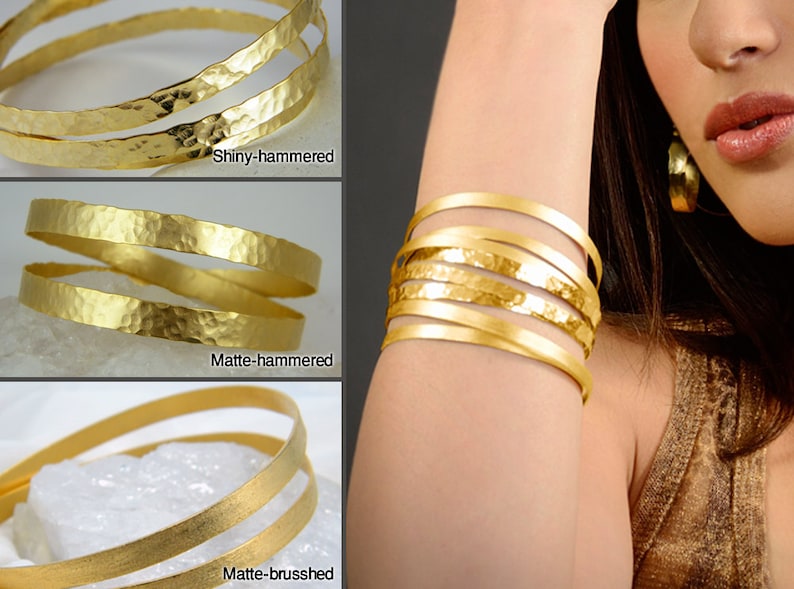 May include: Three gold bracelets with different finishes: shiny-hammered, matte-hammered, and matte-brushed. The bracelets are stacked on top of each other.
