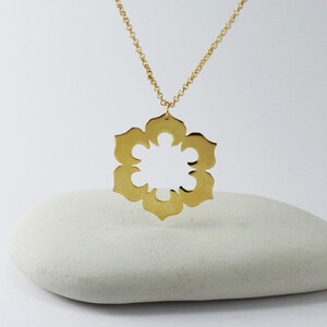 May include: A gold necklace with a large, openwork pendant in the shape of a flower. The pendant is made of a single piece of metal and has a delicate, intricate design.
