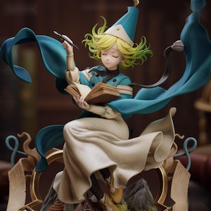 May include: A figurine of a character with short yellow hair wearing a blue pointed hat and a blue and white outfit. The character holds a quill pen and an open book, with a flowing blue cape and a gold-colored decorative base underneath.