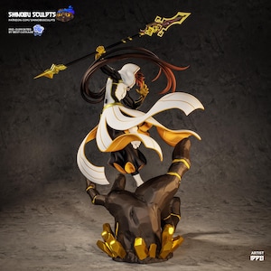 May include: A detailed figurine of a character in a dynamic pose, holding a spear. The figure wears a black and white outfit with gold accents and flowing white fabric. The base is a stylized hand with gold crystal formations.