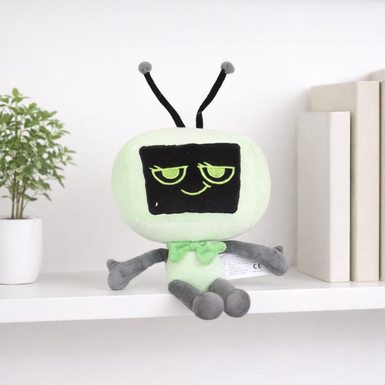 Może przedstawiać: Pluszowa zabawka w kształcie telewizora retro. Zabawka ma jasnozielone ciało, czarny ekran z uśmiechniętą twarzą i dwie czarne anteny z szarymi końc&oacute;wkami. Ma szare ramiona i nogi oraz zieloną muszkę.