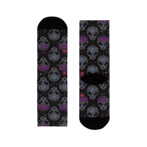 May include: Black socks featuring a repeating pattern of grey and purple alien heads and starbursts. The socks have black heels and toes. The alien heads have large eyes and small mouths.