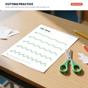 May include: A white paper worksheet titled Cutting Practice with the subtitle scissor skills built the way a left-handed child actually cuts. The page features five green dotted zigzag lines for cutting practice, accompanied by a pair of green scissors.