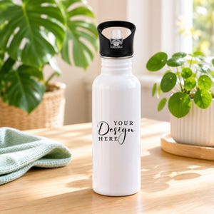 Puede incluir: Una botella de agua blanca con una tapa de rosca negra y una boquilla de plástico transparente. La parte frontal de la botella presenta el texto impreso en negro "YOUR DESIGN HERE" en una combinación de fuente cursiva y sans-serif.