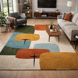 May include: A rectangular area rug featuring a cream-colored background with large, rounded geometric shapes in shades of olive green, light blue, burnt orange, and mustard yellow, accented by thin black line details throughout the pattern.