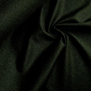 Könnte beinhalten: Ein dunkelwaldgrüner Stoff mit einer weichen, gefilzten Textur. Das Material ist in tiefe, fließende Falten gelegt, die ein Spiel von Licht und Schatten auf der Oberfläche erzeugen und das dichte, matte Finish der Textilfasern hervorheben.