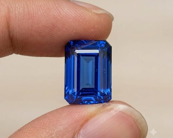 Puede incluir: Una gema de color azul intenso y vibrante, tallada en forma de esmeralda rectangular con facetas nítidas y limpias. La piedra muestra un alto nivel de claridad y un perfil de color rico y saturado, reflejando la luz en su superficie geométrica.