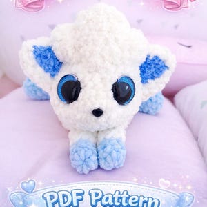 Könnte beinhalten: Ein handgefertigtes weiß-blaues Plüschtier mit großen, glitzernden Augen und dem Text "I know u want me!" und "PDF Pattern". Das Plüschtier hat blaue Akzente an Ohren und Füßen und liegt auf einer lavendelfarbenen Oberfläche.