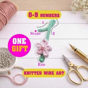 May include: A handmade knitted wire art number one with a pink flower and green stem. The image includes the text "0-9 Numbers", "One Gift", and "Knitted Wire Art". A spool of pink thread, a bowl of metal rings, and gold scissors are also visible.