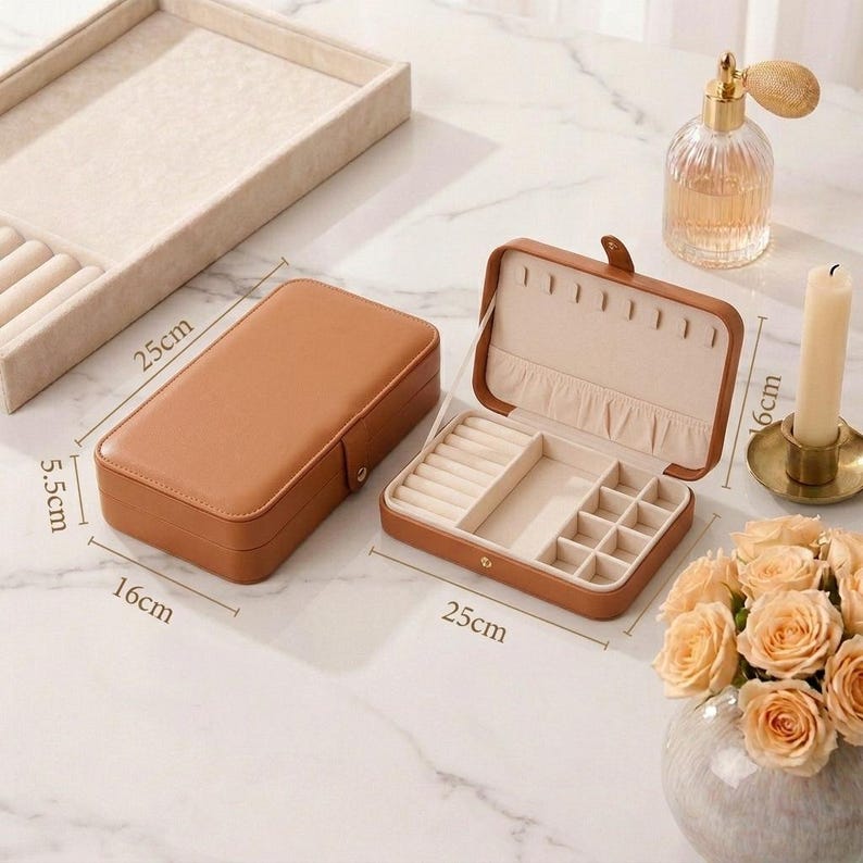 May include: A brown rectangular jewelry box, 25 cm long, 16 cm wide, and 5.5 cm high, with a beige interior. The open box reveals compartments for rings and other jewelry. A matching tray is visible in the background.