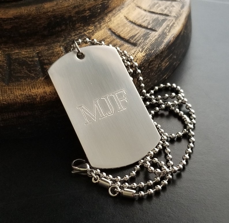 May include: A silver dog tag necklace with a ball chain. The dog tag is engraved with the initials "M.J.F."