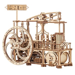 May include: A light brown wooden mechanical model kit featuring a large flywheel, intricate gear systems, and a beam engine design. A sign at the top displays the text WODTRICK. The structure is composed of laser-cut plywood pieces assembled into a complex machine with visible pistons, rods, and a cylindrical base.