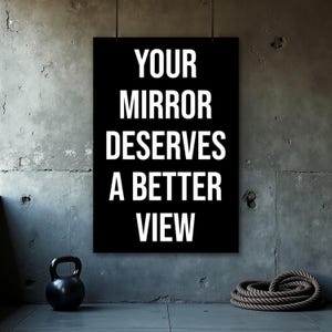 May include: Black poster with the text "YOUR MIRROR DESERVES A BETTER VIEW" in white. A black kettlebell and a coiled rope are on the floor in front of a grey concrete wall.