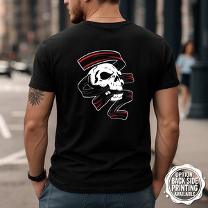 May include: Black t-shirt with a white skull design entwined with a black ribbon and red detailing. The back of the shirt showcases a detailed graphic, appealing to those with an interest in alternative or edgy clothing.