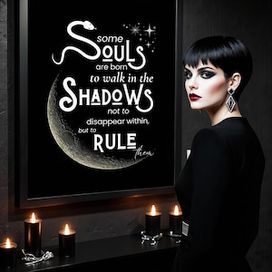 May include: Black framed art print with the text "Some Souls are born to walk in the Shadows". The print features a crescent moon and snake design. The image is set against a dark background with lit candles.