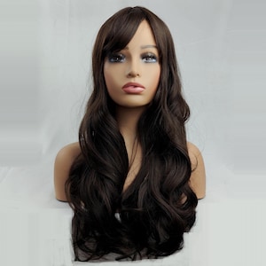 Puede incluir: Una peluca marrón oscuro con cabello largo y ondulado y un flequillo lateral. La peluca se exhibe en una cabeza de maniquí con tez clara y rasgos faciales pintados. El cabello tiene un aspecto y una textura naturales.