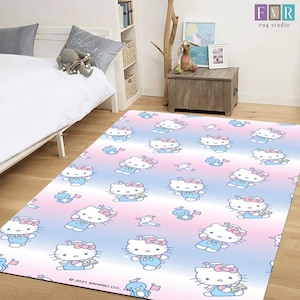 Puede incluir: Alfombra rectangular con un patrón repetido de Hello Kitty con un vestido azul y un lazo rosa. La alfombra tiene un fondo degradado de rosa, azul y blanco. Fabricado por FMR rug studio.