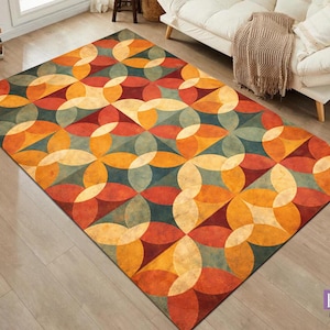 Op de afbeelding: Rechthoekig vloerkleed met een geometrisch patroon in tinten oranje, rood, geel en blauwgroen. Het ontwerp heeft overlappende cirkels en bloembladachtige vormen, wat een retro, modernistische uitstraling uit het midden van de eeuw creëert. Het vloerkleed ligt op een lichte houten vloer.