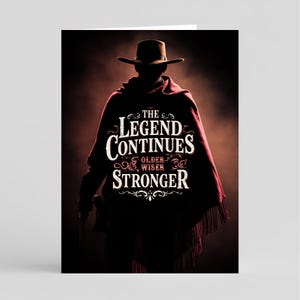 May include: Greeting card featuring a silhouette of a person in a cowboy hat and poncho, holding a gun. The text "The Legend Continues, Older, Wiser, Stronger" is displayed in white. The background is dark with a red and brown gradient.