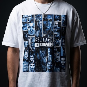 Puede incluir: Una camiseta blanca de manga corta con un gran estampado gráfico en tonos azules de varios luchadores profesionales y el logotipo de WWE SmackDown en el centro. El diseño consiste en un collage de retratos individuales en cuadrícula.