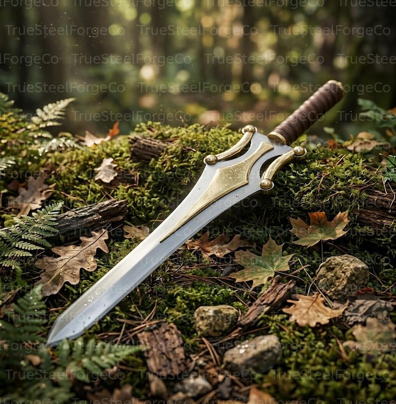 May include: A double-edged sword with a silver blade and a gold-toned crossguard featuring curved accents. The handle is wrapped in brown leather, and the pommel is rounded. The sword rests on a mossy forest floor with scattered brown leaves.