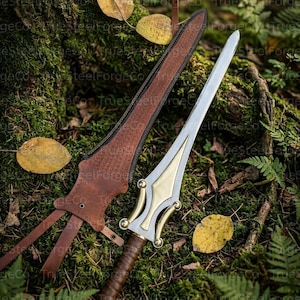 May include: A double-edged dagger with a polished steel blade, a brass-colored crossguard, and a brown leather-wrapped handle. The dagger is accompanied by a matching brown leather sheath featuring decorative stitching and leather straps.