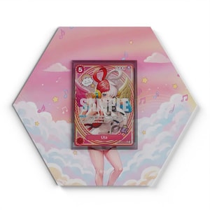 Può includere: Una targa esagonale con uno sfondo di cielo rosa e blu con nuvole, stelle e note musicali. Al centro della targa si trova una carta collezionabile di One Piece del personaggio Uta, inserita in una custodia protettiva trasparente con la scritta SAMPLE.